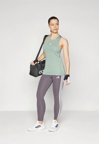 Athletic outfit featuring a mint green tank top, gray leggings with white stripes, and black gym bag. White sports shoes, fingerless gloves.