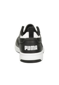 Schwarz-weißer Sportschuh mit einem synthetischen Obermaterial, gepolstertem Kragen, auffälligem Logo an der Ferse und Gummisohle für zusätzlichen Halt.