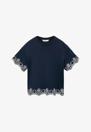 Marineblå bluse med korte ærmer og blomsterblondekant i hvid på ærmerne og nederste kant.