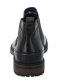 Bottine en cuir noir avec des panneaux élastiques sur les côtés, bout rond, accents bleus sur le talon et semelle extérieure en caoutchouc brun texturé.