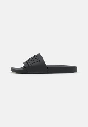 Black slide sandal with a wide strap featuring embossed brand logo, flat sole, and open toe, shown in side profile on white background.
