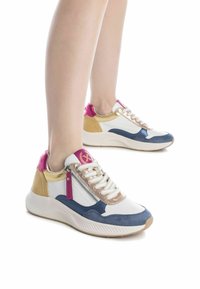 Zapatillas multicolores que combinan materiales en blanco, azul marino, dorado y rosa. El diseño incluye una parte superior texturizada y una cremallera lateral prominente.