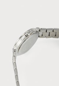 Silver stainless steel watch with a round case, textured crown, and linked bracelet. Smooth finish on the case and a plain watch back.