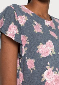 Blommig kortärmad skjorta i marinblått tyg med rosa rosor och gröna löv. Avslappnad passform med rundad halsringning och sidofickor.