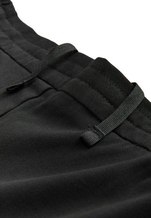 Shorts en coton noir avec une taille élastique, dotés d'un cordon de serrage et de détails de couture discrets près des poches et des bords de la taille.