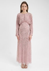 Lang roze jurkje met paillettenversieringen en ingewikkelde patronen, met lange mouwen en een getailleerde taille. Zilveren accenten in het ontwerp.