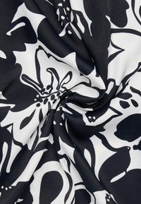 Tessuto floreale in bianco e nero con una superficie liscia, caratterizzato da forme di fiori audaci e elementi astratti in un motivo vorticoso.