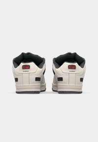 Back view of sneakers with a light gray synthetic upper, black accents, cushioned inner lining, and a textured rubber sole. Logo visible on heel.