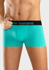 Turquoise boxer briefs with a black waistband featuring the text "no banani." Made from a smooth material with close-fitting design.