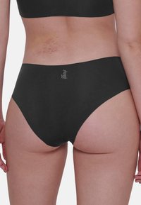 Mutande nere con un design liscio e senza cuciture, caratterizzate da un taglio a vita alta. Il logo del marchio è discretamente visibile sull'elastico in vita.