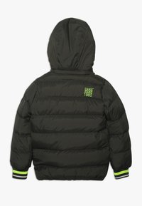 Vadderad svart jacka med huva, som har horisontella sektioner. Grönt logotext på den övre delen av ryggen och ränder på ärmsluten. Lätt material.