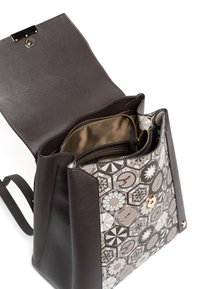 Sac à dos en cuir marron avec un devant en tissu à motifs. Il dispose d'une fermeture éclair dorée, de poches intérieures et d'une fermeture à pression magnétique.