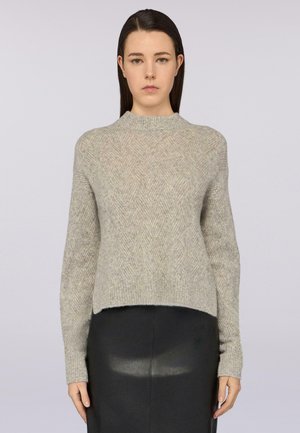 Pull en maille texturée gris clair avec un motif en losanges, col côtelé et manches longues ; porté sur une jupe en cuir noir.