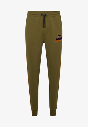 Pantalones jogger verde oliva con rayas laterales naranjas, cintura con cordón negro y un pequeño logo púrpura-naranja en la parte superior del muslo izquierdo.