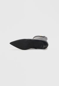 Bottine en cuir noir à bout pointu, avec un talon fin et un détail de boucle décoratif. Texture lisse avec une finition mate sur la semelle.