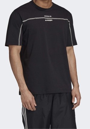 Schwarzes Baumwoll-T-Shirt mit kurzen Ärmeln, versehen mit weißen Adidas- und Spdp-Logo-Drucken, akzentuiert durch weiße Nähte entlang der Schultern.