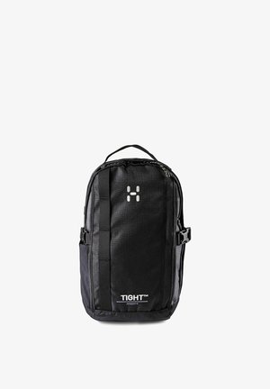 Sac à dos compact noir avec poignée supérieure, sangles latérales à boucle, sangle verticale frontale et étiquette « TIGHT Junior 8 » sur le panneau inférieur avant.