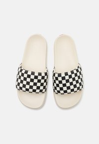 Black and white checkered slide sandals with a wide strap and a beige footbed. Soft material with a smooth surface and rounded edges.