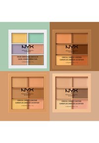 Quatre palettes de correcteurs de couleur contenant six nuances chacune, avec des tons variés de crème, pêche, jaune et brun. Étuis blancs et bruns.