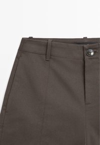 Brune bomuldsbukser med en glat tekstur, der har en frontknaplukning og syede lomme detaljer, som viser et skræddersyet design.