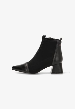 Botín negro con punta afilada, laterales elásticos y un detalle de cuero texturizado cerca de la base. Presenta un tacón cuadrado y un acabado suave.