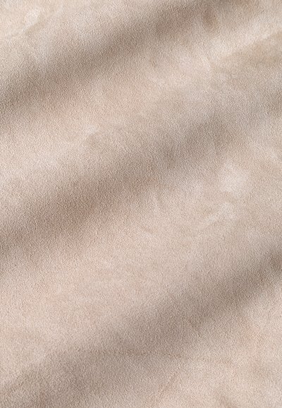 Beiger Wildlederstoff mit einer glatten, weichen Textur, der subtile Farbvariationen und ein einheitliches Oberflächenmuster aufweist.