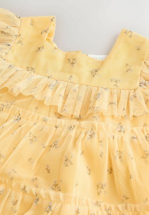 Dzeltena ziedu raksta kleita ar volānu apkakli un slāņiem. Izgatavota no viegla auduma ar maziem, smalkiem ziedu rakstiem.