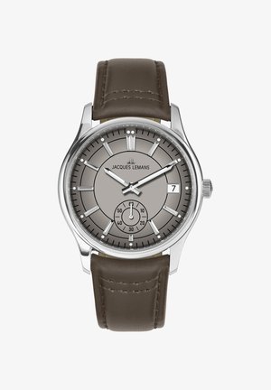 Čelični sat sa sivim brojčanikom, srebrnim kazaljkama, prikazom datuma i podbrojčanikom. Smeđi kožni remen s naglašenim šavovima. Moderan, okrugli dizajn.