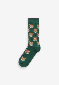 Grüne Socken mit einem wiederholten Muster von orangen Tigerköpfen, einem festen lila Bündchen oben und einer glatten Textur.
