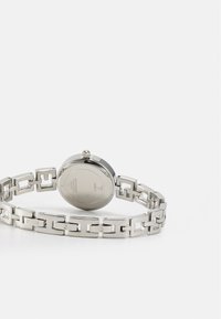 Roestvrijstalen horloge met een ronde kast en schakelarmband. Gepolijste oppervlakte, ronde wijzerplaat, zichtbare hardware en gegraveerde merknaam.