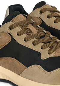 Zapatillas con un upper de ante negro y marrón, acentos texturizados en beige y cordones redondos marrones. Presentan una suela acolchada y detalles cosidos.