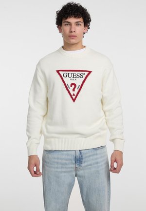 Cream sweater with a ribbed hem and cuffs. Features a red triangle logo with "GUESS" and a question mark at the center. Casual fit.