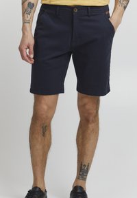 Marineblaue Shorts aus Baumwolle mit geradem Schnitt, Knopfverschluss, zwei Fronttaschen und sichtbaren Nähten.