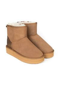 Botas de tobillo de ante color marrón claro con un suave forro blanco interior, suela de goma plana y un acento brillante en el panel trasero.
