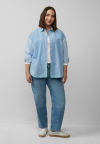 Hellblau-weiß gestreiftes Button-up-Hemd, lockere Passform, kombiniert mit ausgebleichten blauen Jeans und weißen Sneakers mit beigen Akzenten.