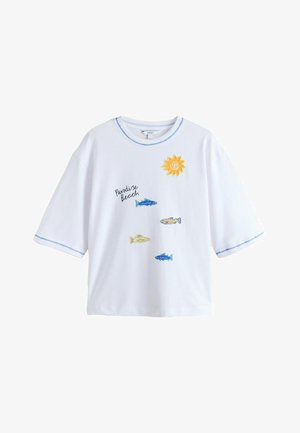 Cămașă albă cu mâneci scurte, cusături albastre în zigzag, grafică cu soare, patru pești colorați și text „Paradise Beach” pe față.