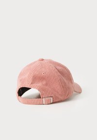 Pink corduroy cap with a curved visor, adjustable strap at the back, and vertical ribbed texture. Displays ventilation holes on the sides.
