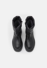 Schwarze Stiefel mit einem glatten Lederaußenmaterial, gepolstertem oberen Teil mit gestepptem Design und einer strukturierten Sohle für besseren Halt. Reißverschluss an der Seite.