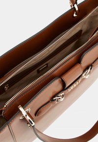 Borsa a mano in pelle marrone con chiusura a zip, tasche interne, hardware argentato e design strutturato. Texture liscia e dettagli a contrasto.