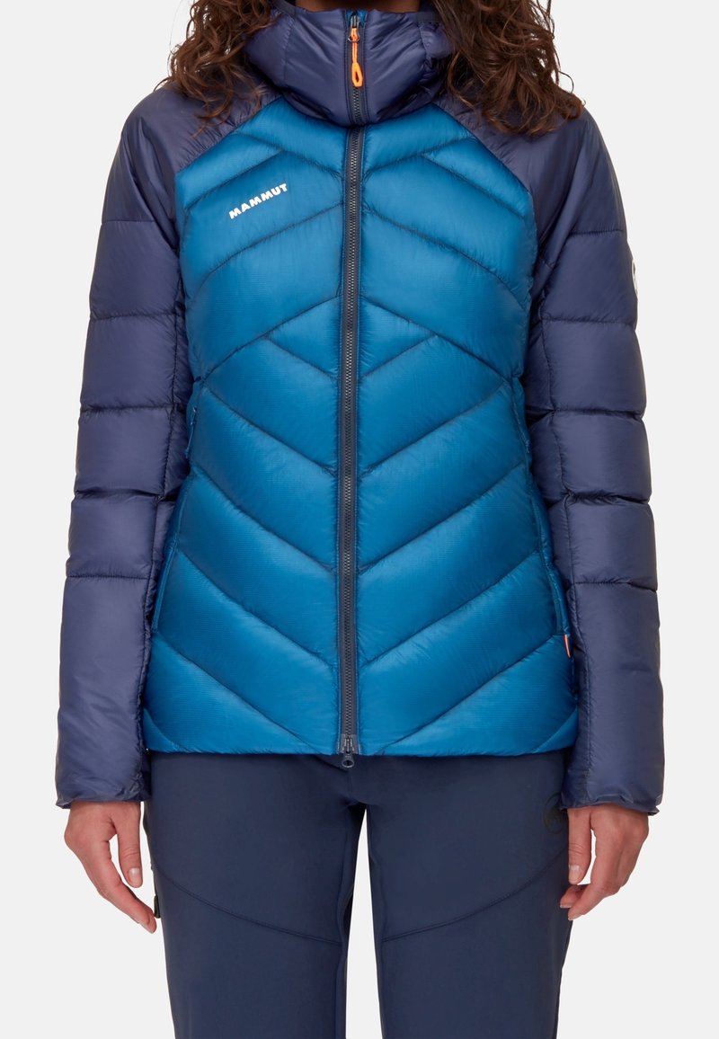 Giacca isolante blu e navy con motivo a zigzag, collo alto, zip completa e logo sul petto. Texture liscia e design gonfio.