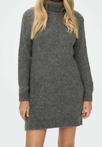 Grå stickad klänning med hög polokrage, långa ärmar och ribbad fåll. Texturen verkar mjuk och varm, lämplig för kallare väder.