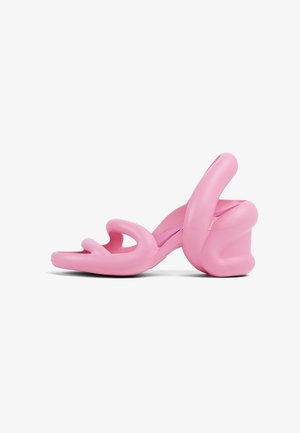 Pink sculptural high-heeled sandals featuring a wavy design and a chunky heel, made of smooth plastic with cutouts in the toe area.
