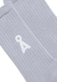 Grijze geribde sokken van zachte stof, met een wit logo 'A' aan de zijkant. De textuur is geweven met een rekbare, comfortabele pasvorm.