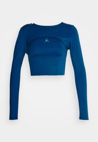 Dlouhý rukáv, zkrácený top v hluboké modré látce. Má kulatý výstřih a malé logo v mátové zelené na hrudi. Hladká textura.