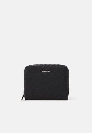 Černá zipová peněženka Calvin Klein s vyraženým logem a geometrickým vzorem. Obsahuje hladký povrch a zip v stříbrném tónu. Kompaktní obdélníkový tvar.