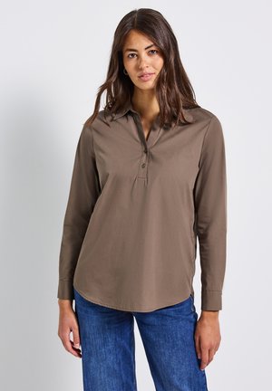 Bruine collshirt met lange mouwen, knoopsluiting en zijsplitsen, gecombineerd met blauwe jeans. Gladde textuur en een ontspannen pasvorm.