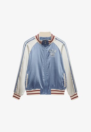 Jasnoniebiesko-biała sportowa kurtka zapinana na zamek, z czerwono-paskowanym kołnierzem i mankietami, z haftowanym logo USA 83 na piersi.