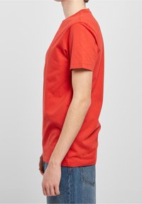 Rode katoenen T-shirt met een klassieke ronde hals, korte mouwen en een rechte snit, gecombineerd met lichtblauwe denim jeans.