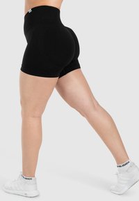 Hoge taille zwarte shorts gemaakt van zacht materiaal, met een gladde textuur en een getailleerd ontwerp, gecombineerd met witte sneakers met enkelondersteuning.