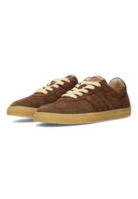Sneakers de ante marrón con cordones crema, con un perfil bajo, suela de goma y detalles de costura sutiles en los costados.
